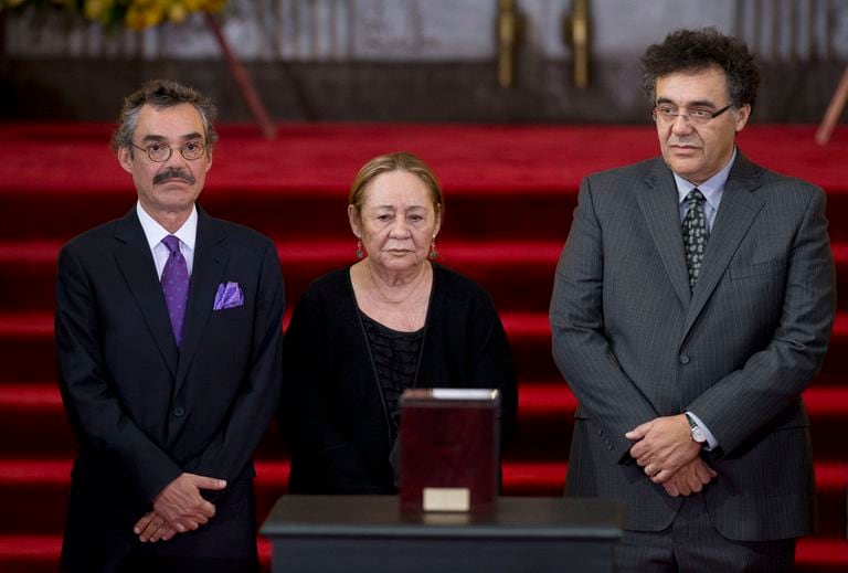 En esta fotografía de 2014 Mercedes Barcha, viuda del Premio Nobel de Literatura colombiano Gabriel García Márquez, es acompañada por sus hijos Gonzalo, izquierda, y Rodrigo junto a la urna con las cenizas de García Márquez en el funeral del escritor en el Palacio de Bellas Artes en México