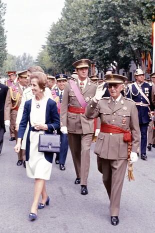 El príncipe Juan Carlos y la princesa Sofía caminan detrás de Franco y su mujer, María del Carmen Polo Martínez-Valdés, durante un desfile militar.