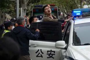 La policía se lleva a un manifestante en medio de una protesta en Shanghai.