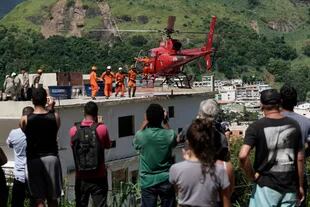 Residentes observan un helicóptero de rescate que transporta una mujer herida en el barrio de Muzema, en Río de Janeiro