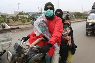 Una familia en moto, con barbijos, en Karachi, Paquistán