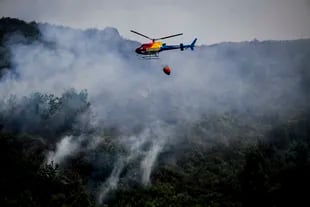 A firefighting helicopter flies over a forest fire near the town of Bustelo in Amarante, northern Portugal on July 16, 2022. 