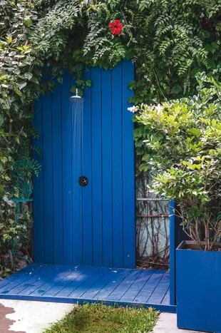 Rodeada de plantas, la ducha se encuentra en una estructura de madera pintada con esmalte sintético azul. Paisajismo: Eugenia Anaya. 