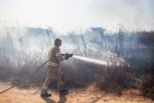 Un bombero israelí apaga el fuego en un campo cercano a la ciudad de Sderot, tras el estallido de un cohete palestino que no fue destruido por la Cúpula de Hierro en tanto se dirigió a una zona despoblada.