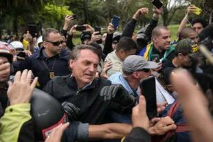 Brazilian President and re-election candidate Jair Bolsonaro greets supporters during a motorcade on the eve of the presidential election, in Sao Paulo, Brazil, on October 1, 2022. - Brazilians go to the polls Sunday in South America's biggest economy, plagued by gaping inequalities and violence, where voters ar expected to choose between far-right incumbent Jair Bolsonaro and leftist front-runner Luiz Inacio Lula da Silva, any of which must garner 50 percent of valid votes, plus one, to win in the first round. (Photo by ERNESTO BENAVIDES / AFP)