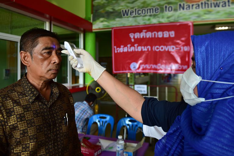 Una enfermera le toma la temperatura a un pasajero antes de subir a un ómnibus en Narathiwat, Tailandia