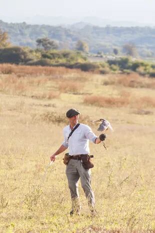 En el campo, François sostiene un halcón en su guante, ya sin la caperuza y previo a que el ave rapaz remonte vuelo en busca de una corriente de aire que lo ayude a subir.