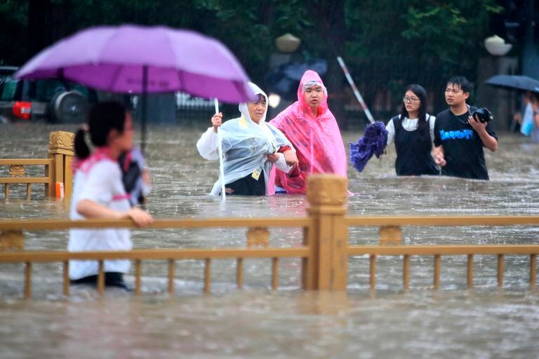 Personas caminan en calles inundadas en Zhengzhou, provincia de Henan, China.