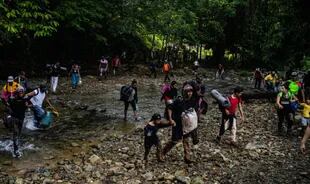 Un grupo de migrantes cruzaban un arroyo en el Tapón del Darién en Panamá. Es una zona difícil donde algunos han perdido la vida