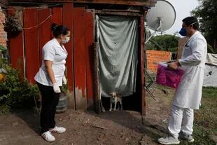 Dos trabajadores del Ministerio de Salud esperan a que el ocupante salga para hacerse la prueba del COVID-19 en Limpio, Paraguay, finalmente la enfemera entró con equipo de protección, por que la mujer que estaba adentro estaba muy enferma