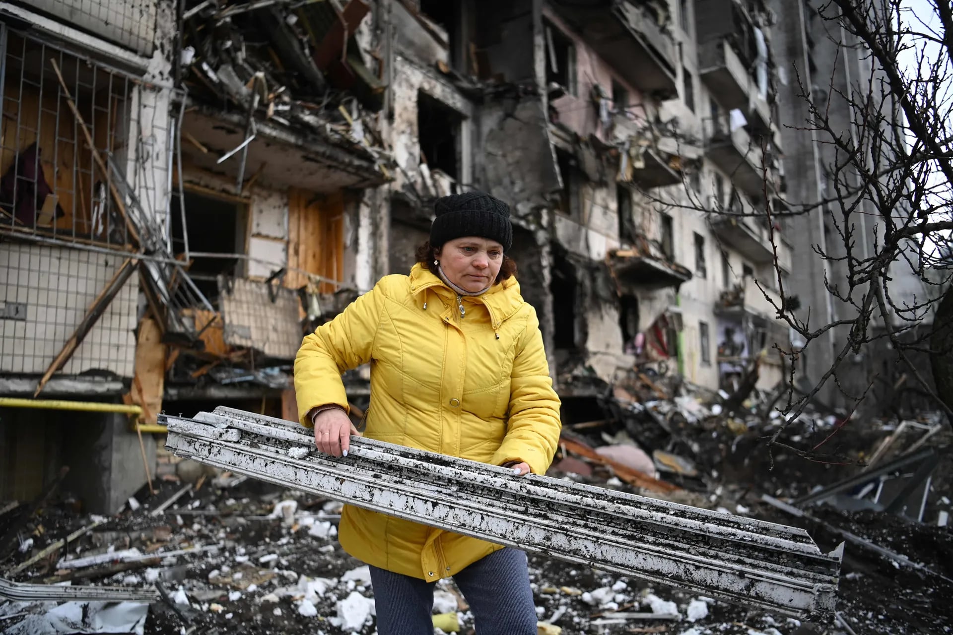 Una mujer limpia los escombros de un edificio residencial dañado en la calle Koshytsa, un suburbio de la capital ucraniana, Kiev
