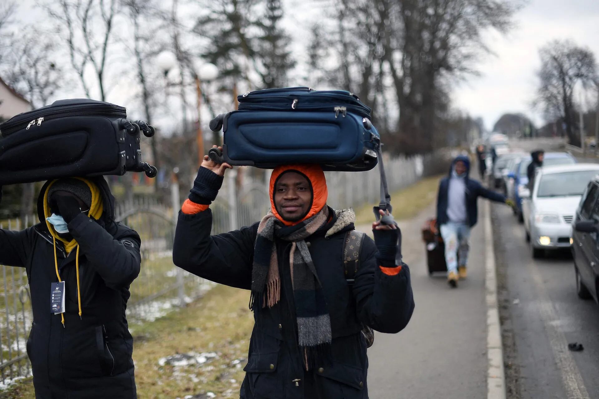 Dos personas caminan con las valijas en sus cabezas, mientras se dirigen a la frontera con Polonia en un intento de huir de Ucrania.