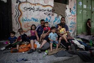 Una familia en Gaza se sienta afuera de su casa después de que fue alcanzada por un ataque aéreo israelí