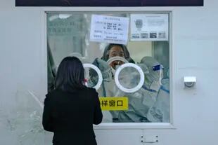 Un hombre abre la boca para una prueba de COVID-19 en un centro de pruebas en Pekín, el martes 6 de diciembre de 2022. 