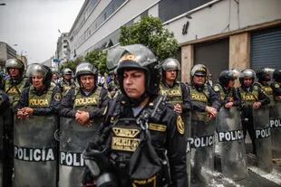 Miembros de la policía vigilan a manifestantes, simpatizantes del presidente de Perú Pedro Castillo, celebrando la noticia del cierre del Congreso