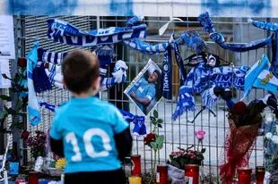 Un niño con la camiseta número 10 del Napoli se detiene junto a los recuerdos de Diego Armando Maradona en una de las valla del estadio San Paolo en Nápoles