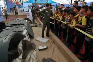 Un miembro de la Guardia Revolucionaria de Irán muestra a un grupo de niños, los restos de un drone Global Hawk estadounidense derribado por fuerzas iraníes en el Estrecho de Ormuz